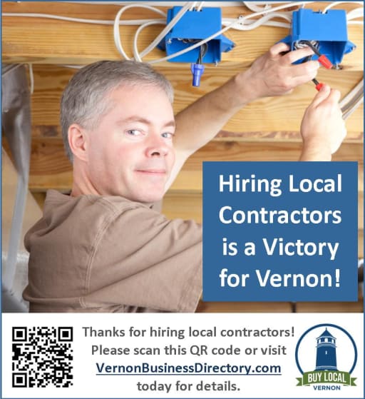 A man is working on electrical wiring in a ceiling, smiling at the camera, with a message promoting local contractors in Vernon.