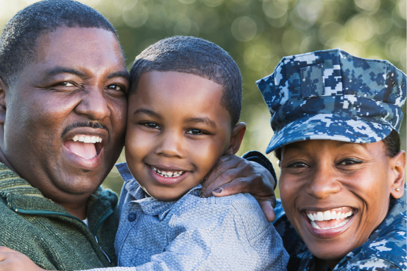 A family: an adult male, a boy, and an adult woman in uniform, all smiling and standing together.