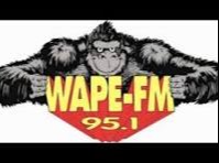 Logo of WAPE-FM 95.1 featuring a gorilla holding a red shield with text on a white background.