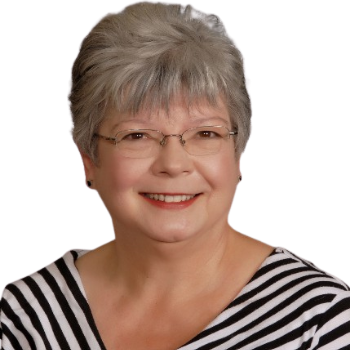 A smiling older woman with short gray hair and glasses, wearing a black and white striped shirt.