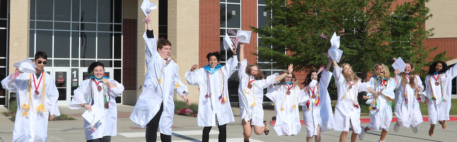 yukon students at graduation jumping in the air