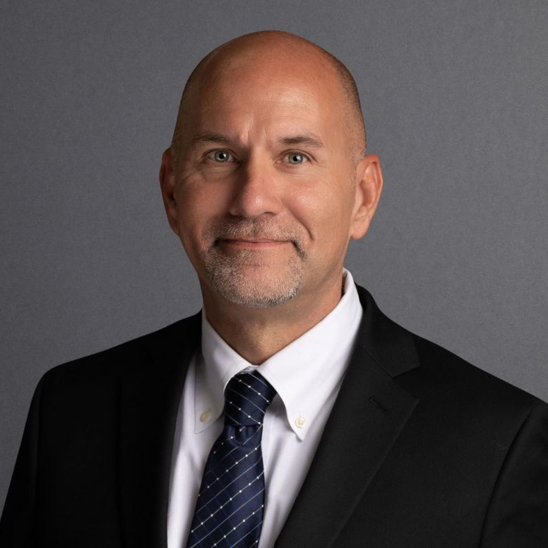 A smiling man wearing a white shirt and a  tie.