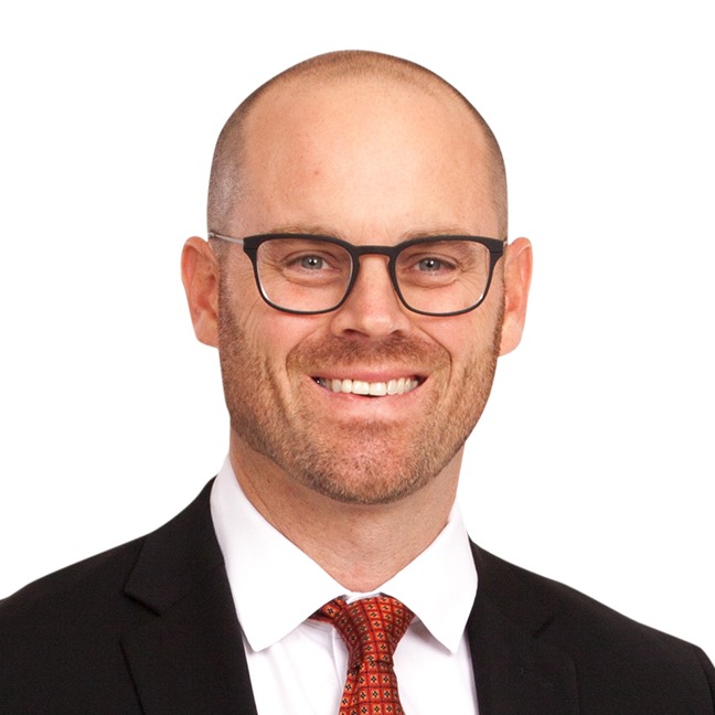 A smiling man with a black suit on a white background