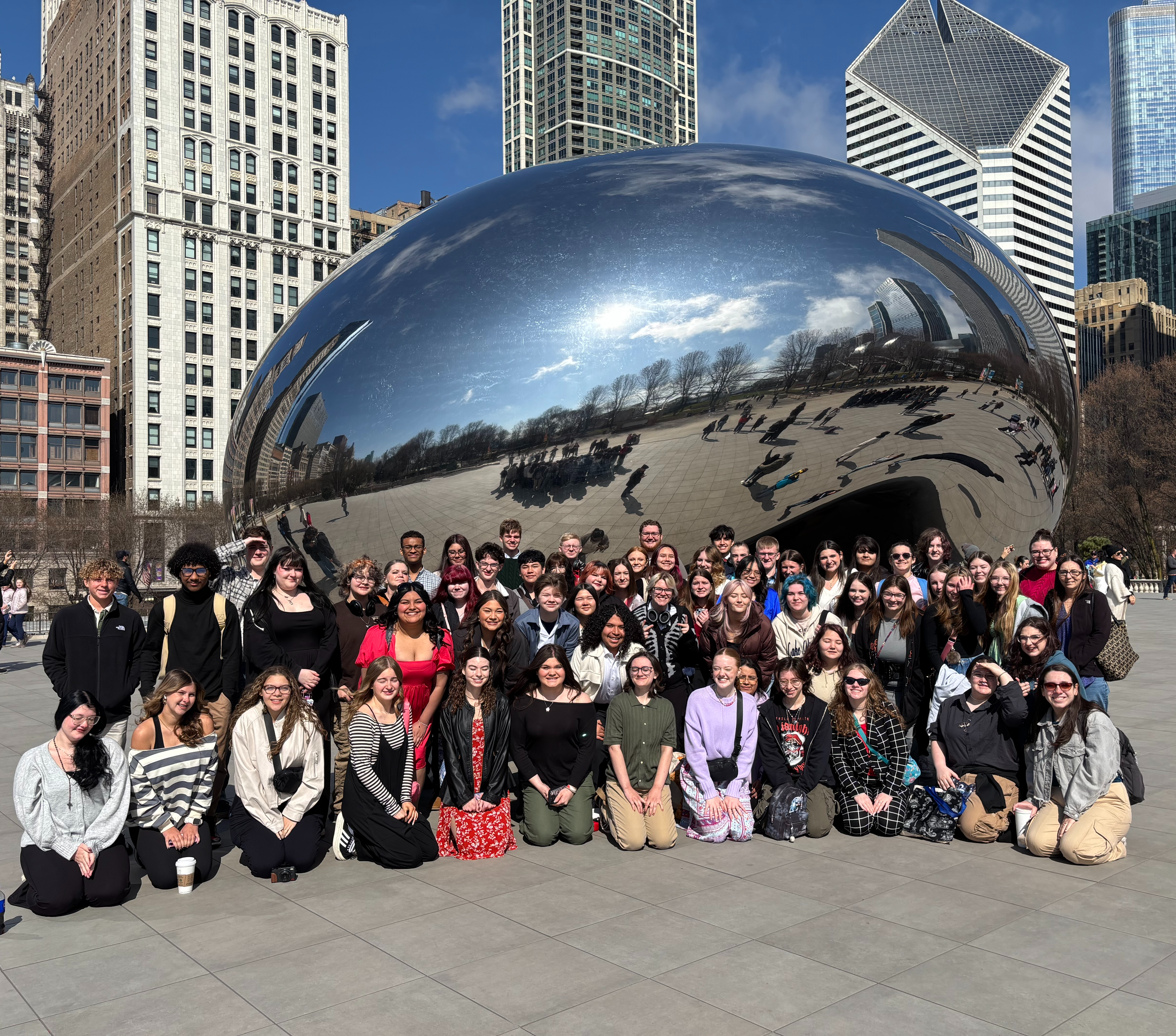 Students pose at a landmark in Chicago, Illinois. Students are set against a city skyline.