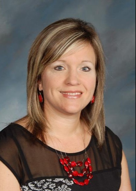 Woman with blonde highlights wearing black top and red beaded necklace