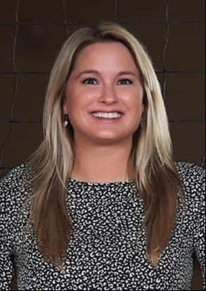 Woman with long, blonde hair wearing a floral black and white top smiing.