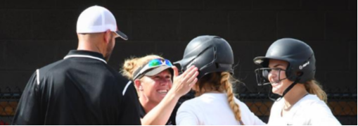 Coaches patting softball student helmet