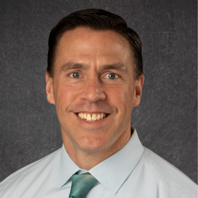 Man smiling with a green shirt and green tie