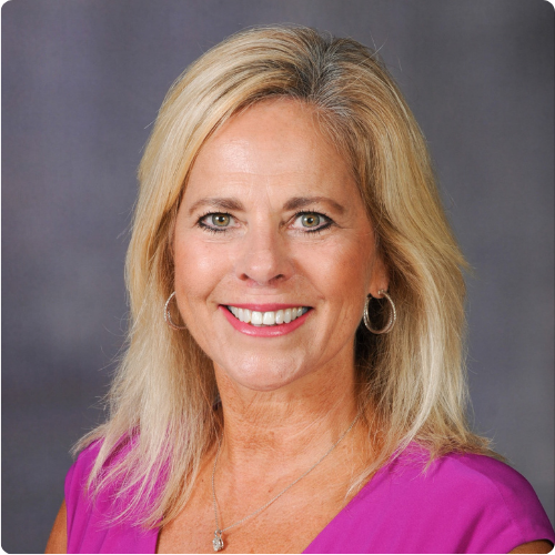 Woman with blonde hair and a pink shirt smiling
