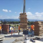 A construction site where wooden boards are being stacked and a forklift is at work.