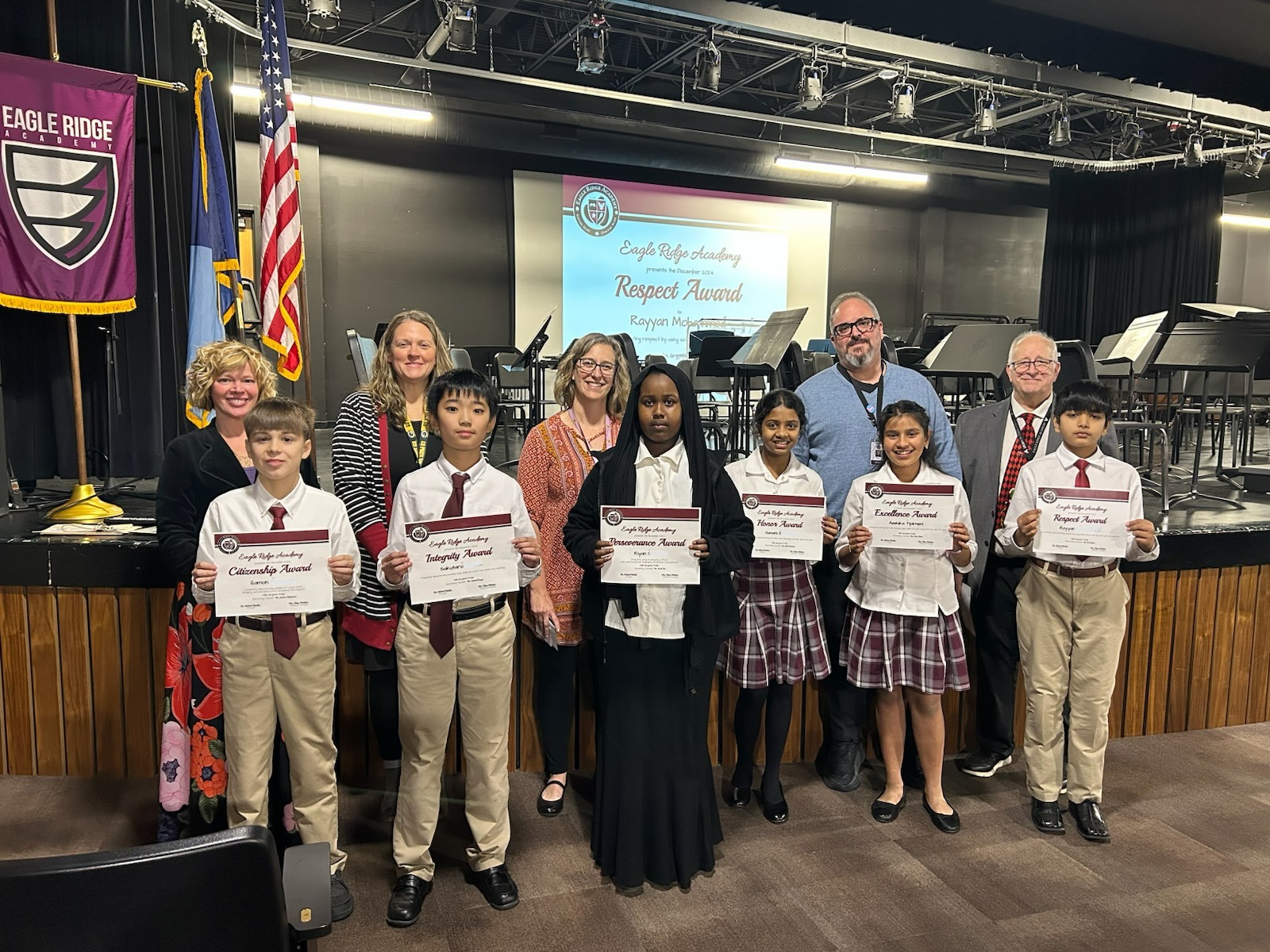 students in uniform posing with teachers and certificates