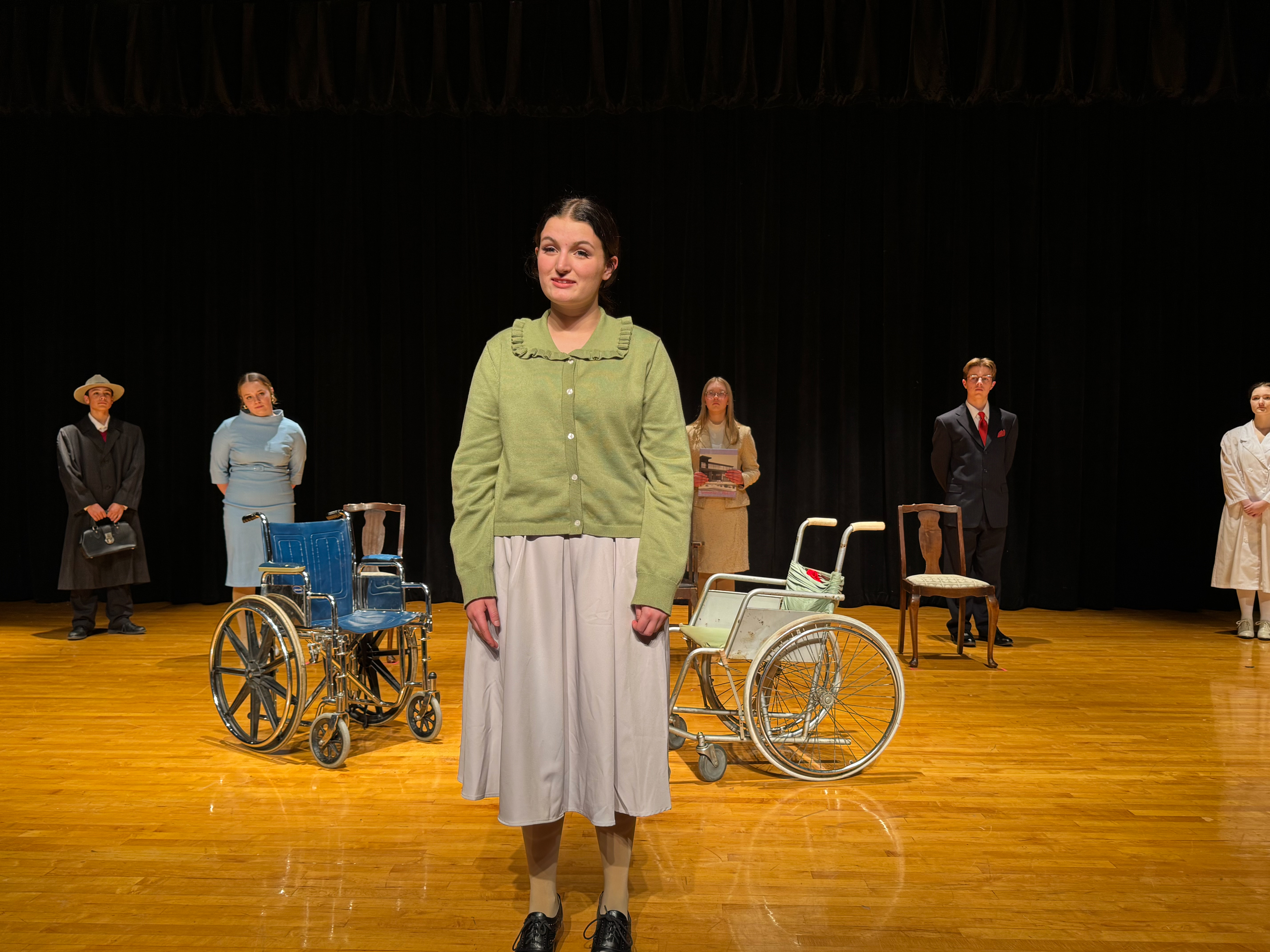 Actress standing in front of two wheelchairs.