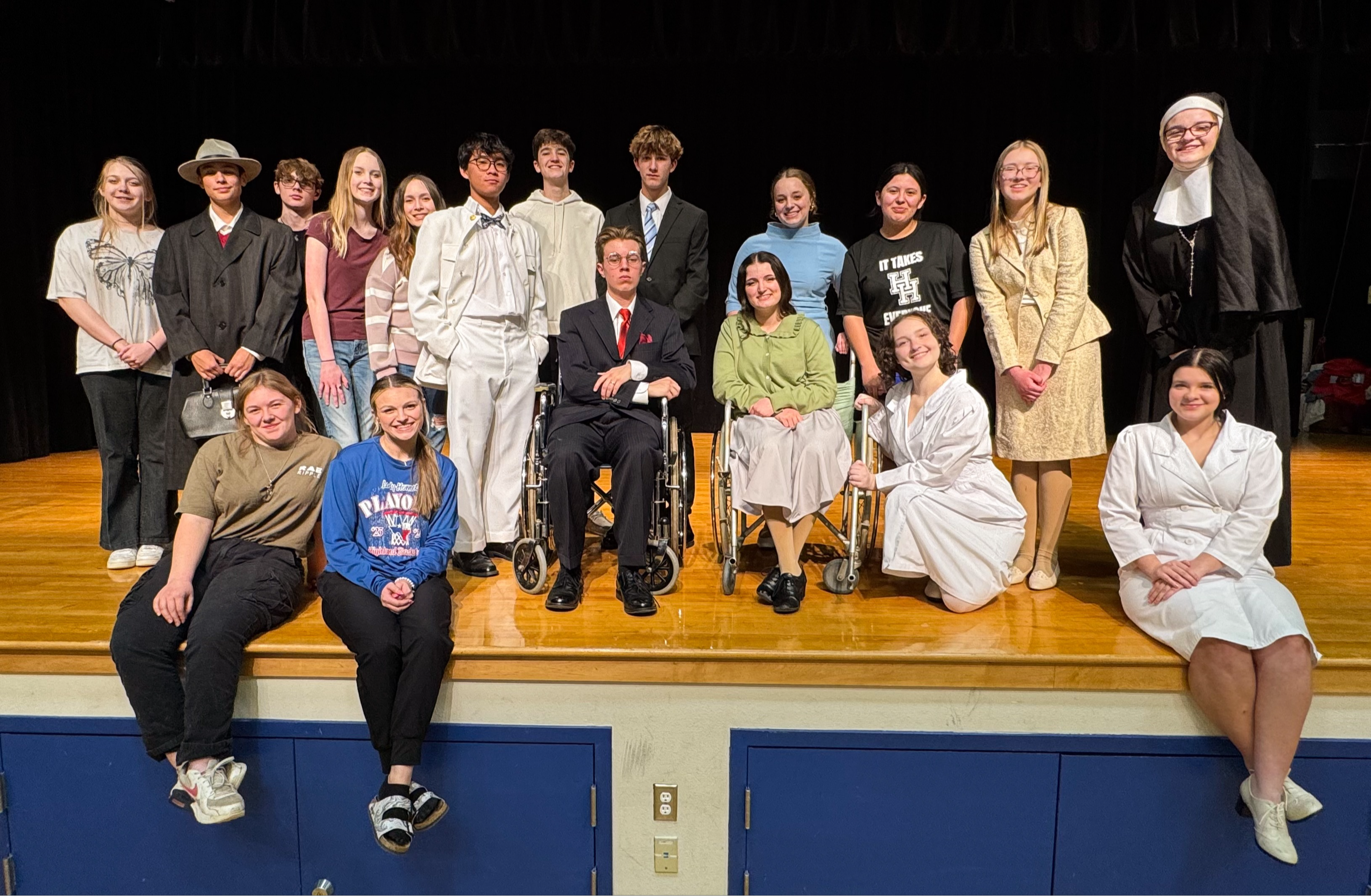 Students in cast in costume in a group photo on stage.