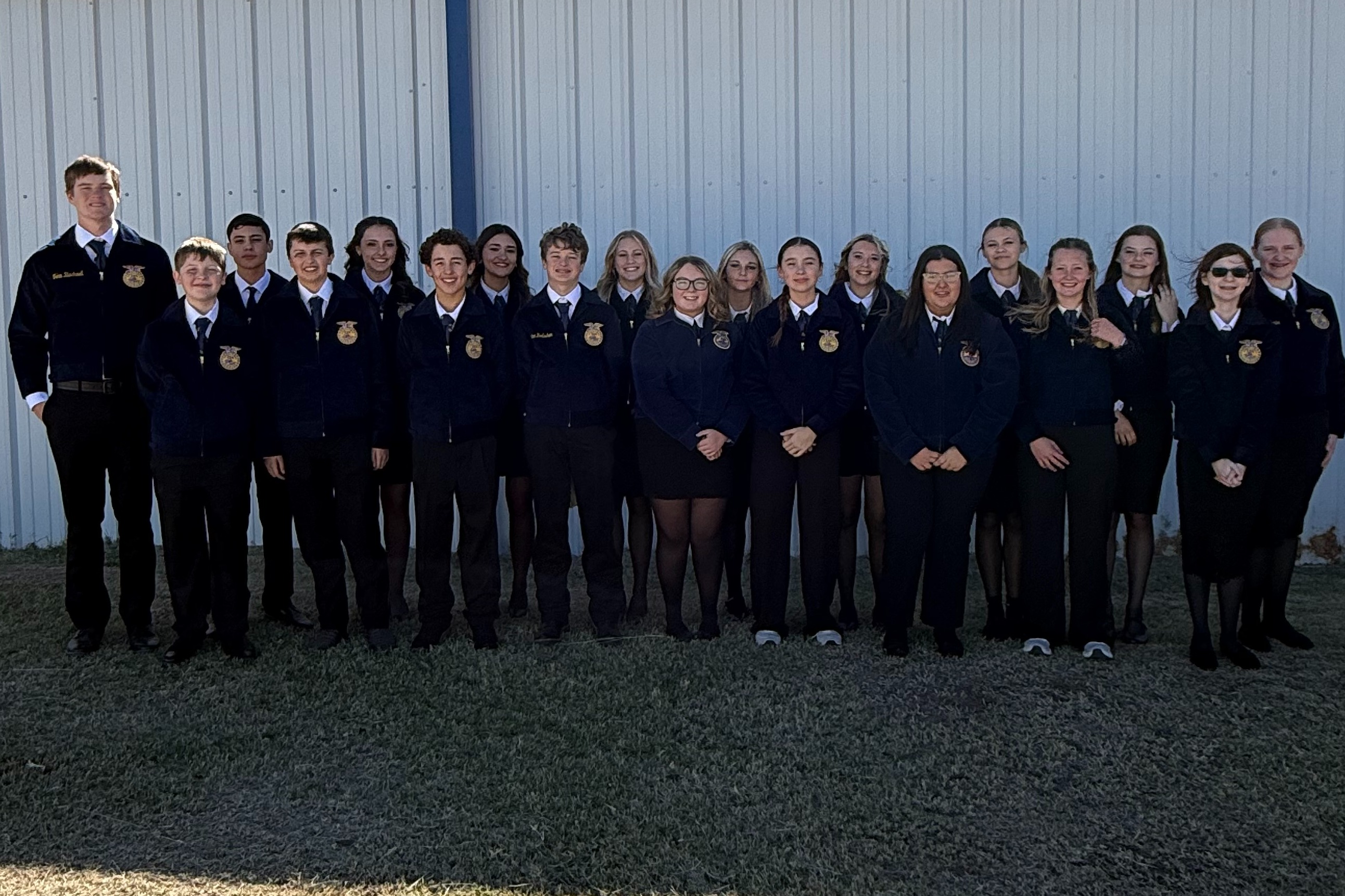 Students wearing FFA official dress standing in front of bus