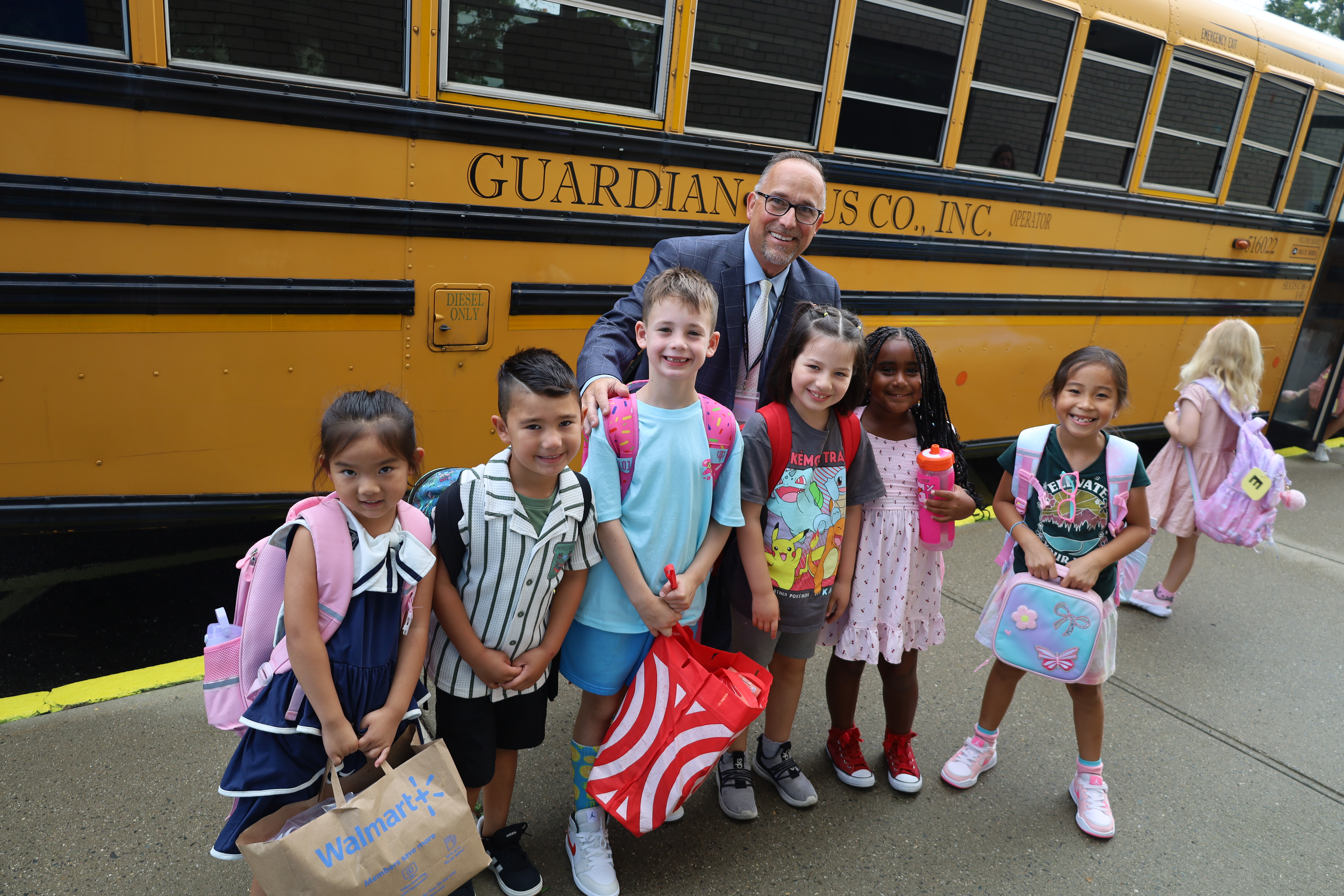 Students outside with principal by bus.