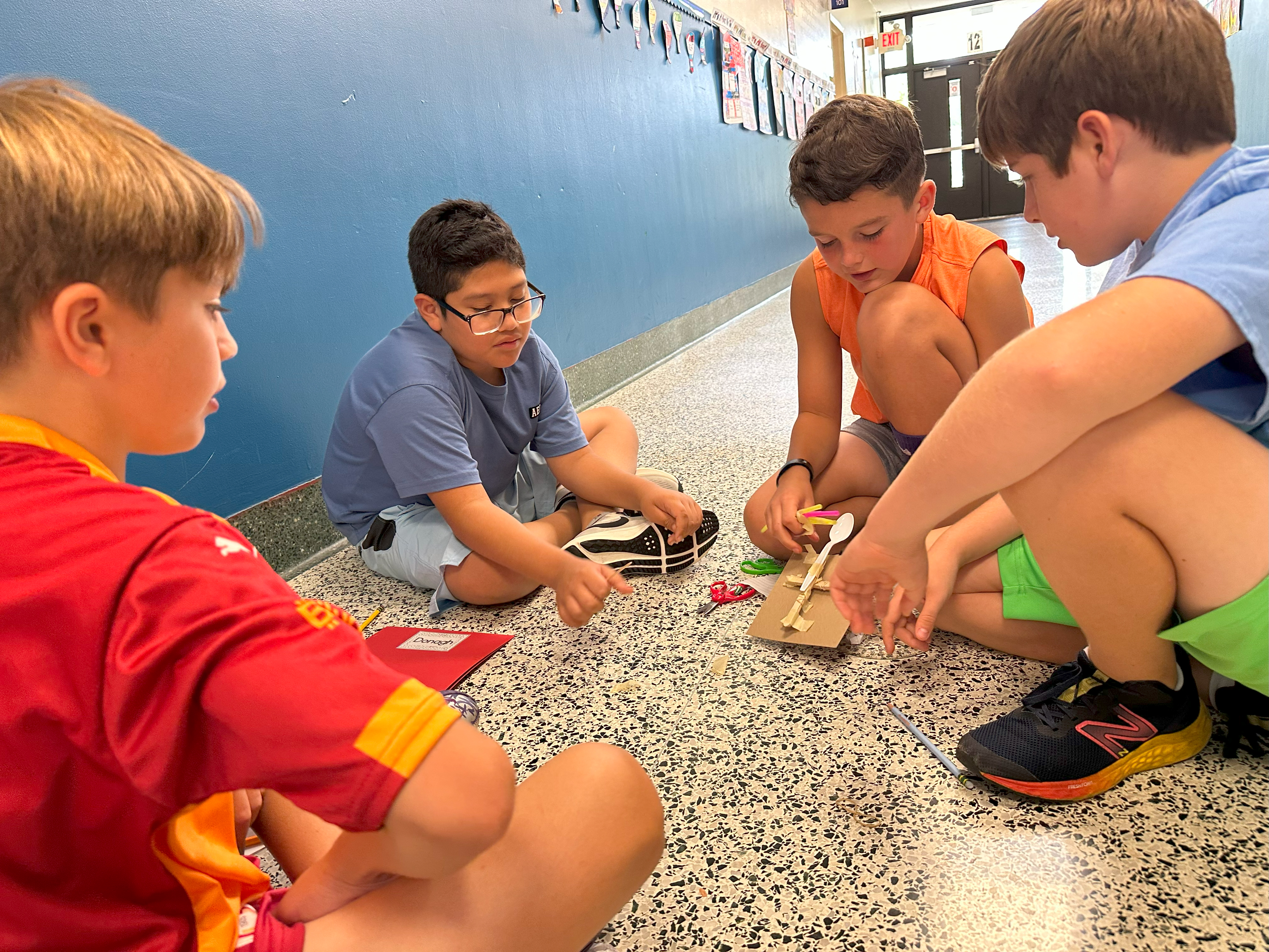 Students making catapults out of wood and spoons.