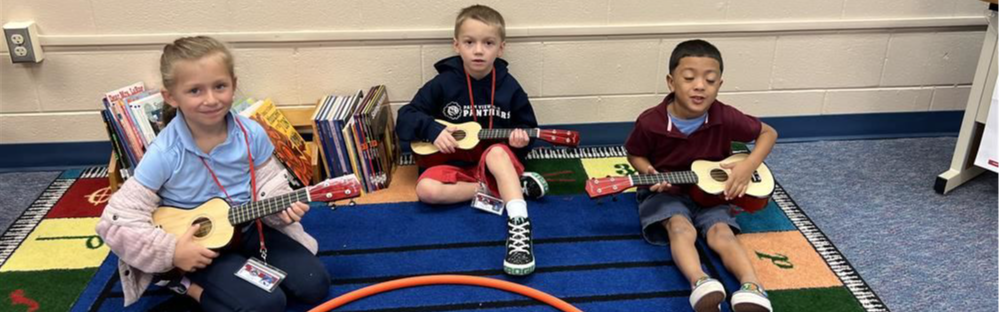 three students small guitars together during class