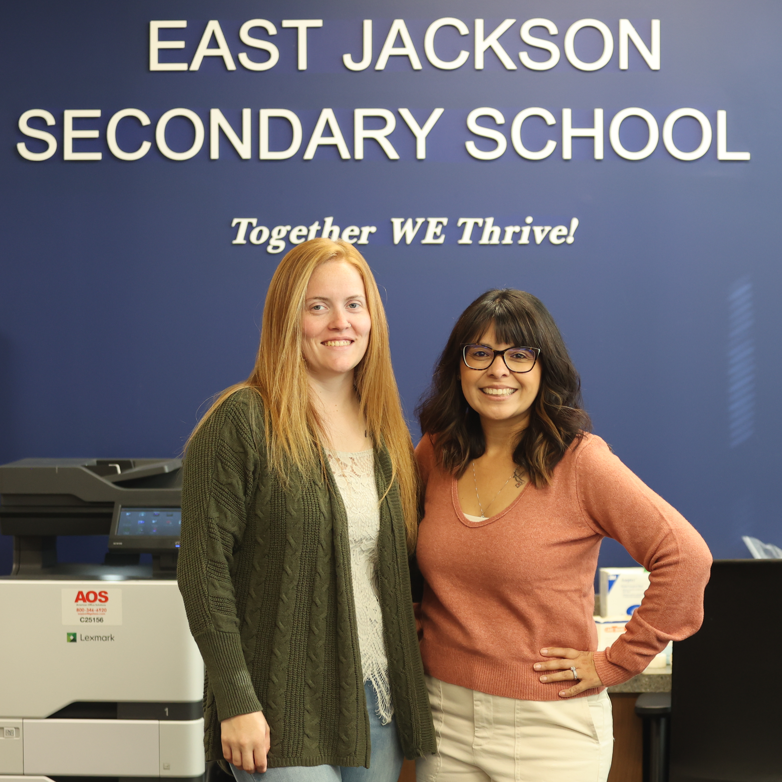 Two women posing in front of East Jackson Secondary School logo
