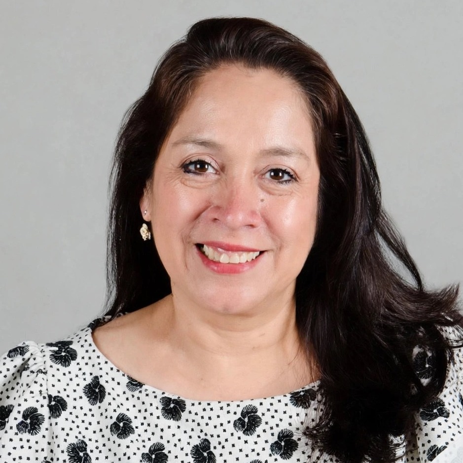 A woman in a white and black shirt with long brown hair smiling.