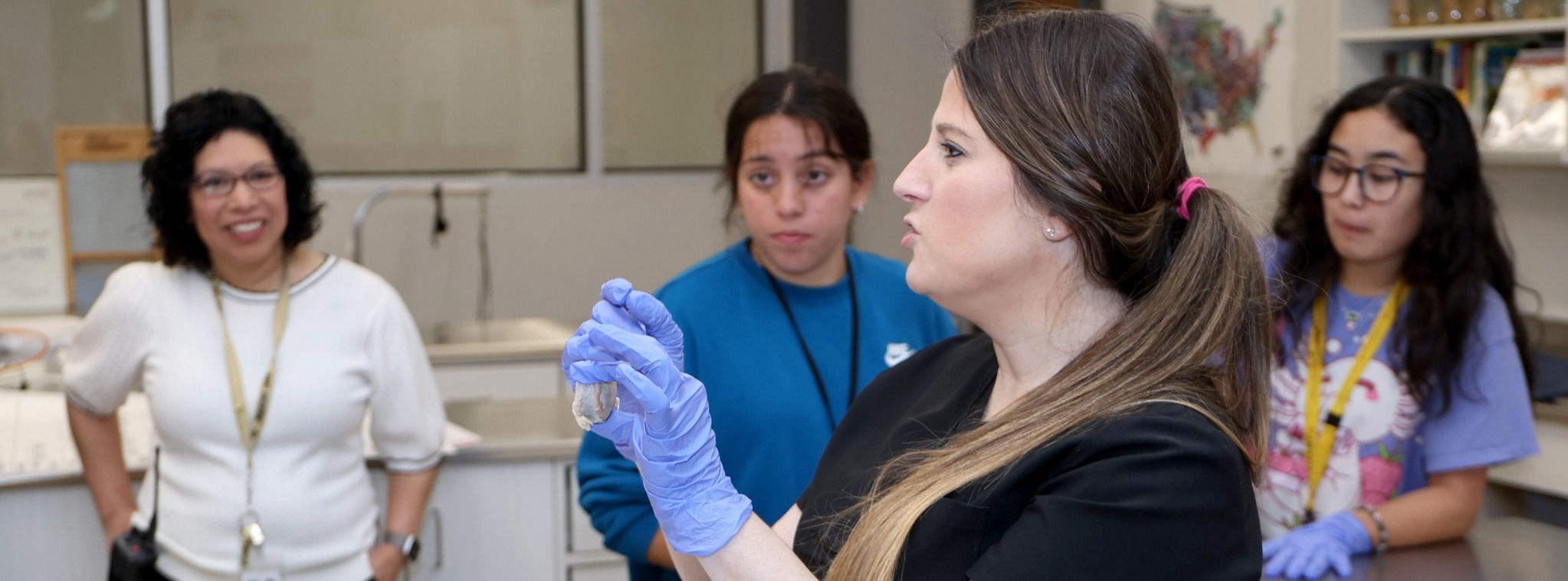 Teacher holding a mineral in front of the class while students listen.