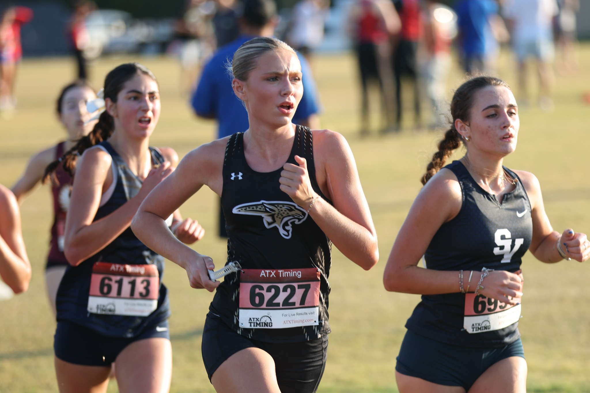 A John High School cross country runner running alongside other runners from other school districts.