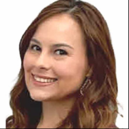 A woman with long brown hair smiling at the camera from a slight side angle.