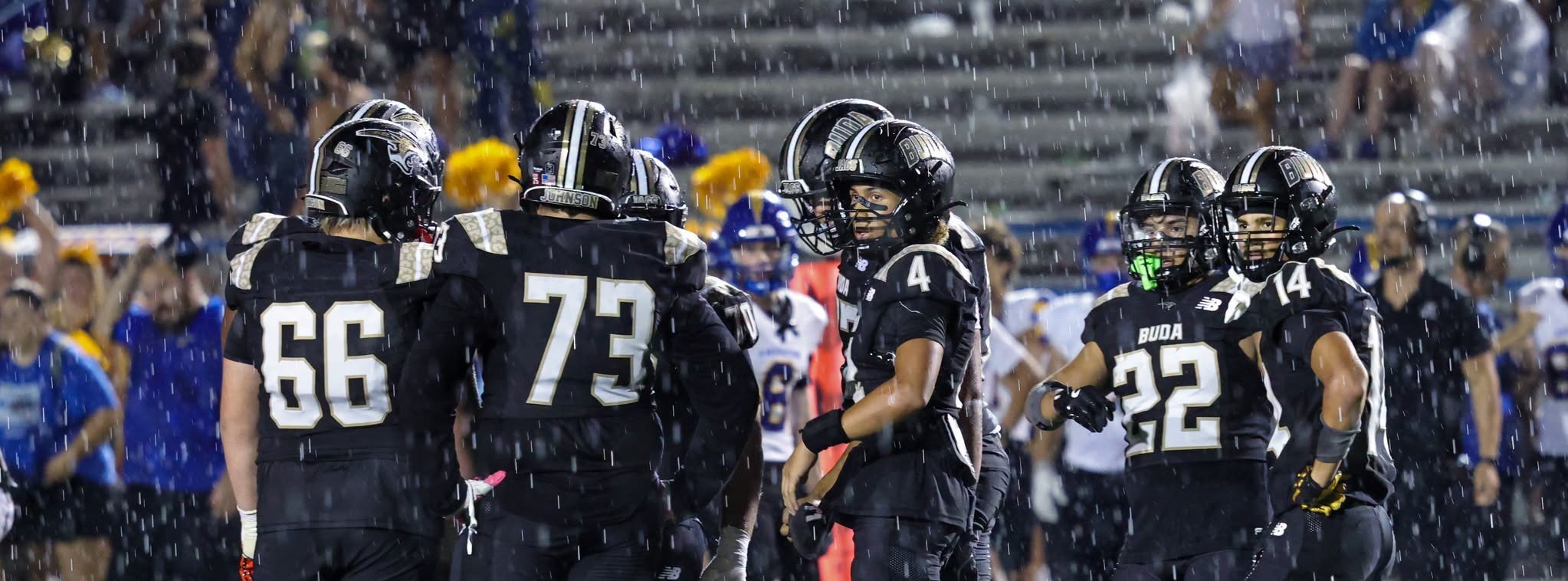 Johnson High School football players huddled up while standing in the rain.