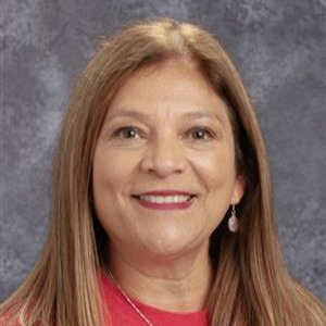 A smiling woman with shoulder length brown hair in a red shirt against a gray background.
