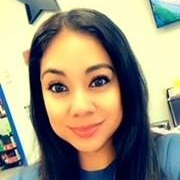 A grinning woman with long black hair in a blue shirt.