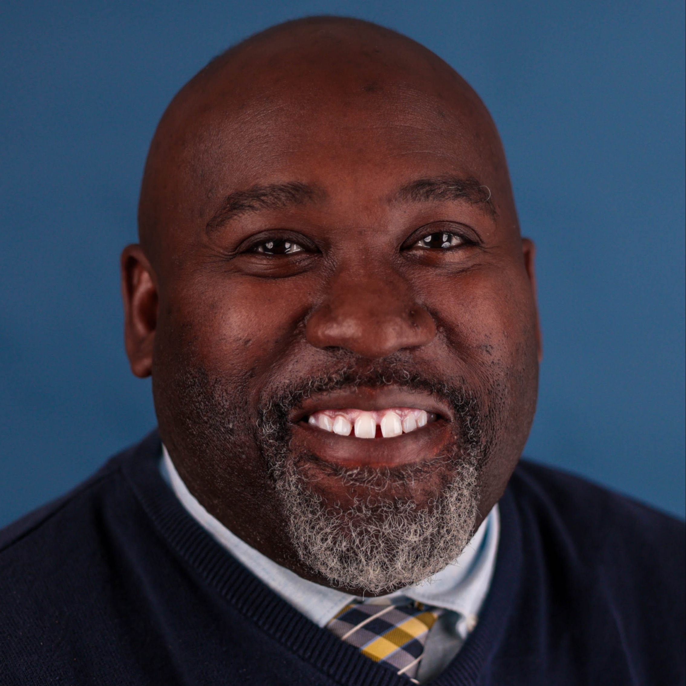 A smiling man posing for a photo in front of a professional photography background.