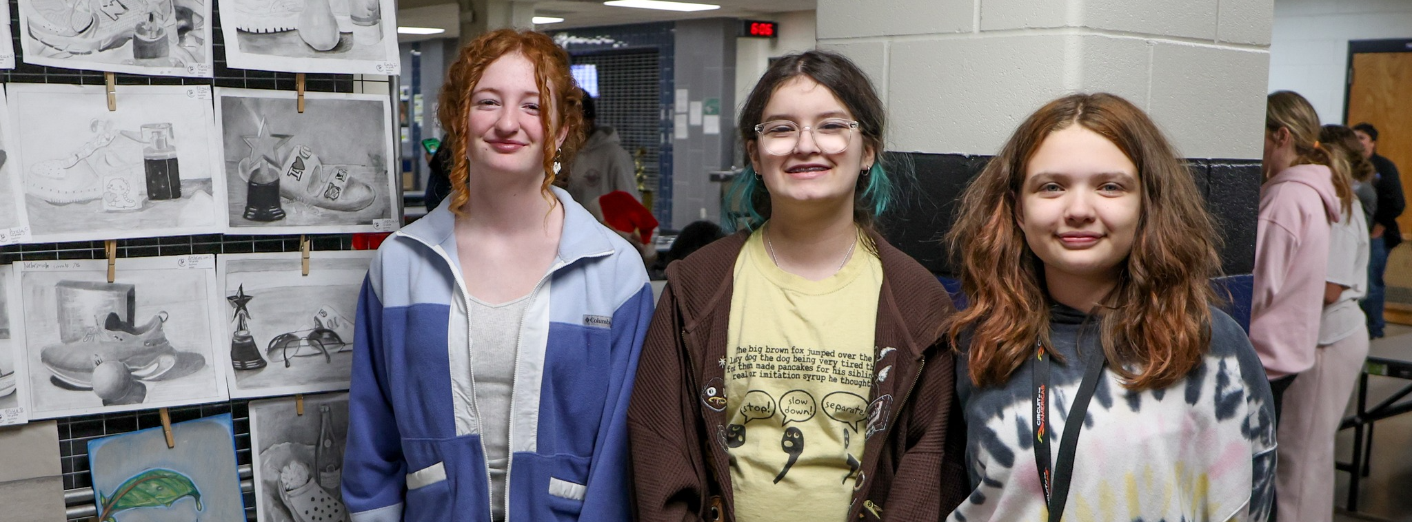 Students standing in front a wall of student art