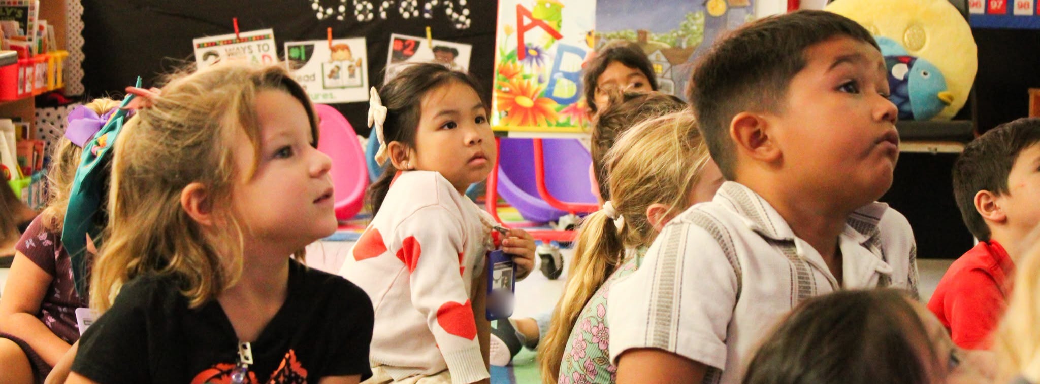 A classroom of students listening to their teacher who is out of frame.