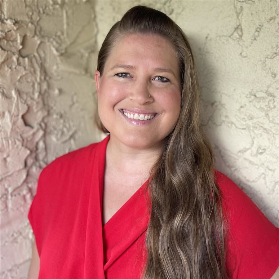 A woman in a red shirt with blonde hair smiling