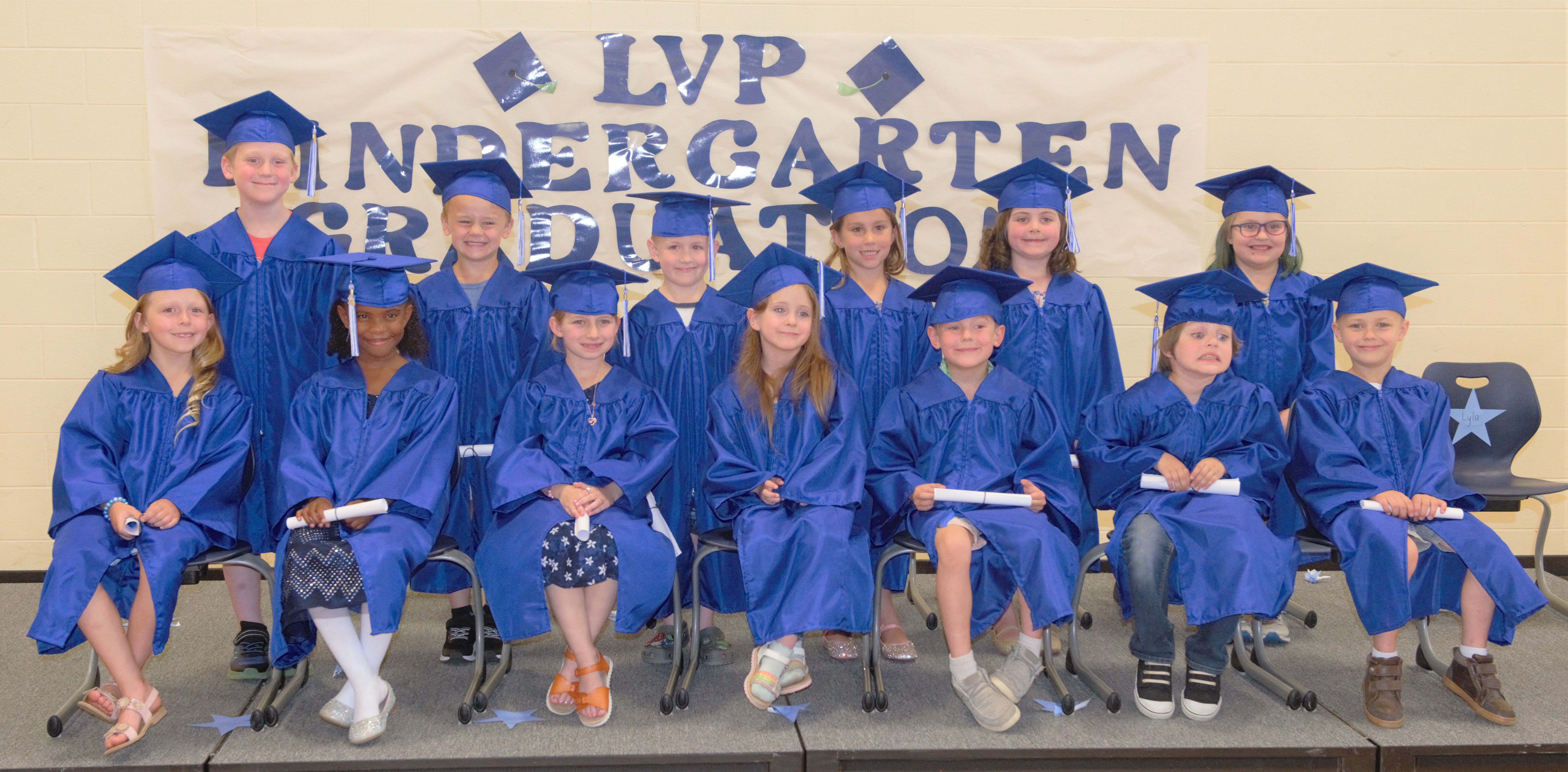 Kindergarten graduation ceremony with boys and girls in blue caps and gowns