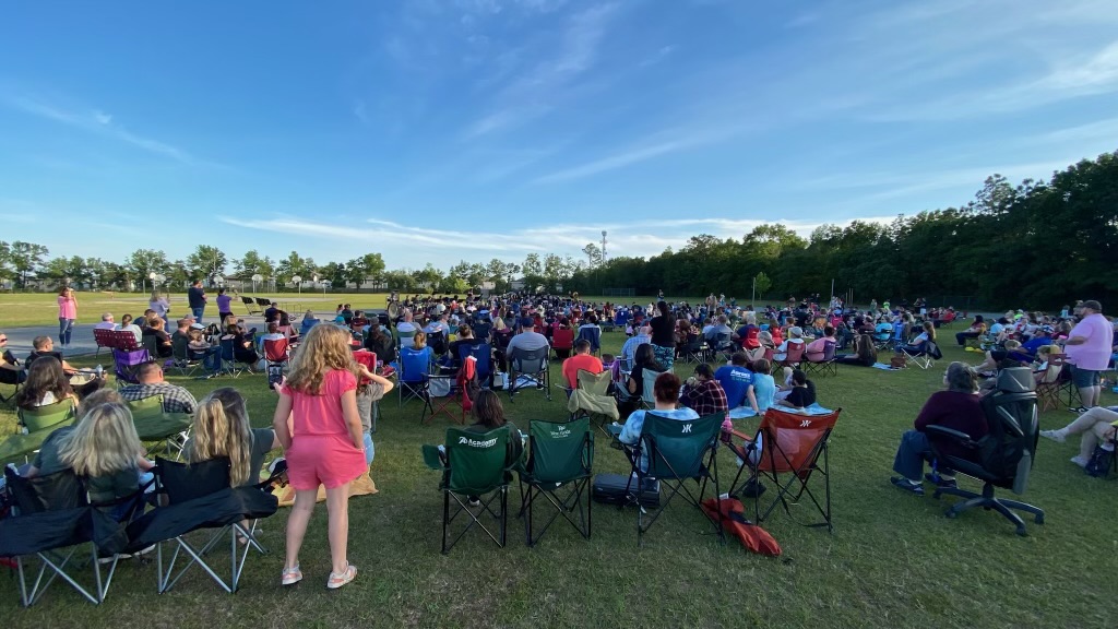 A lively outdoor music event with a large band performing on stage.