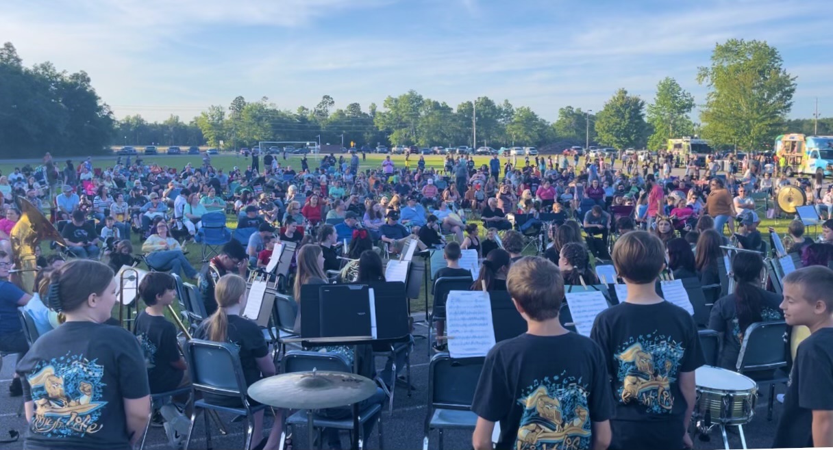 A lively outdoor music event with a large band performing on stage.