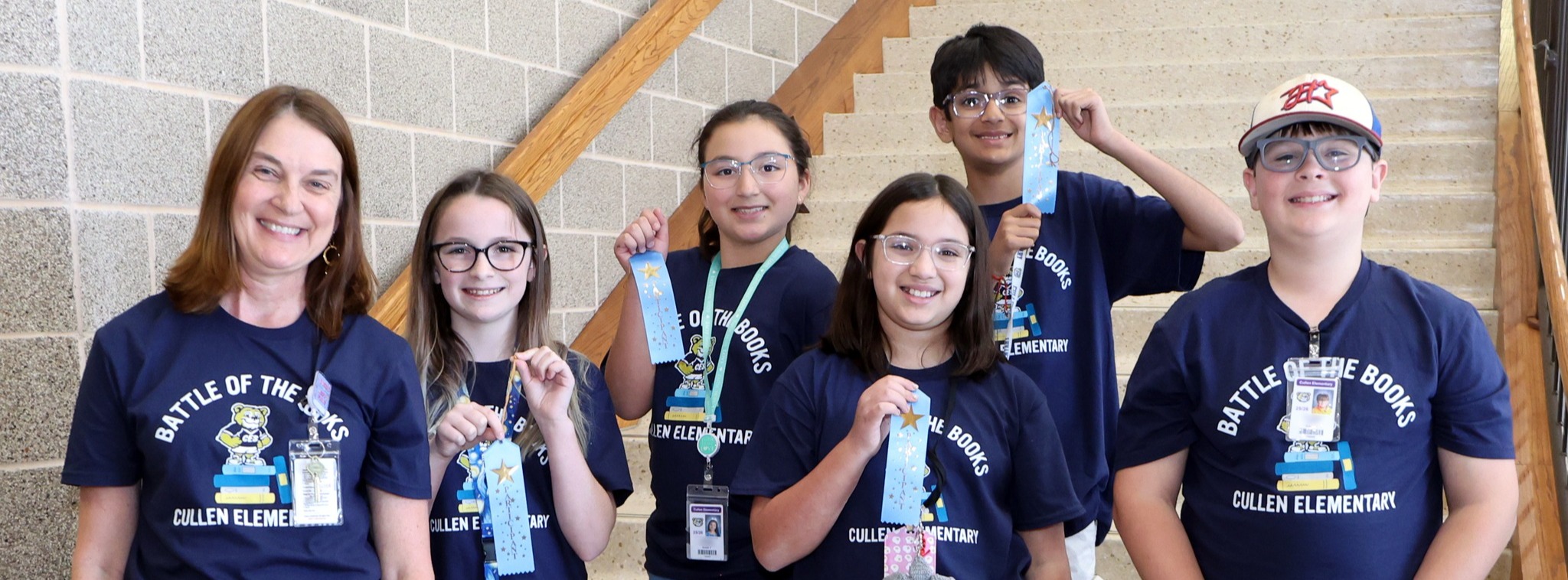 A group of five smiling students and a teacher wearing matching shirts while posing for a group photo.