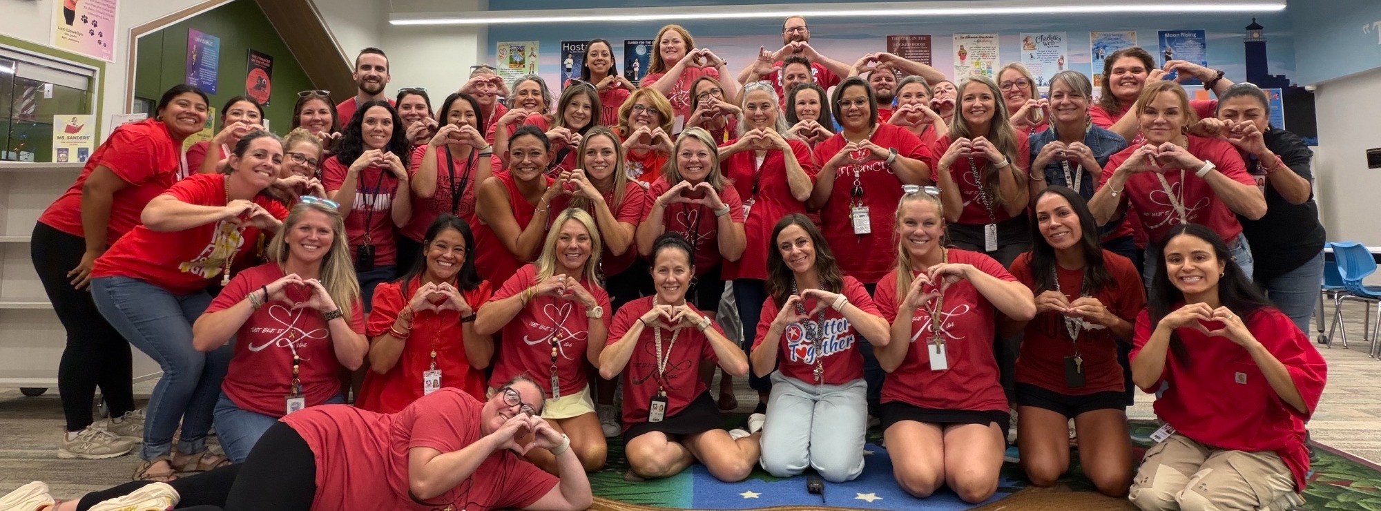 A group of 40+ people making a heart shape with their hands.