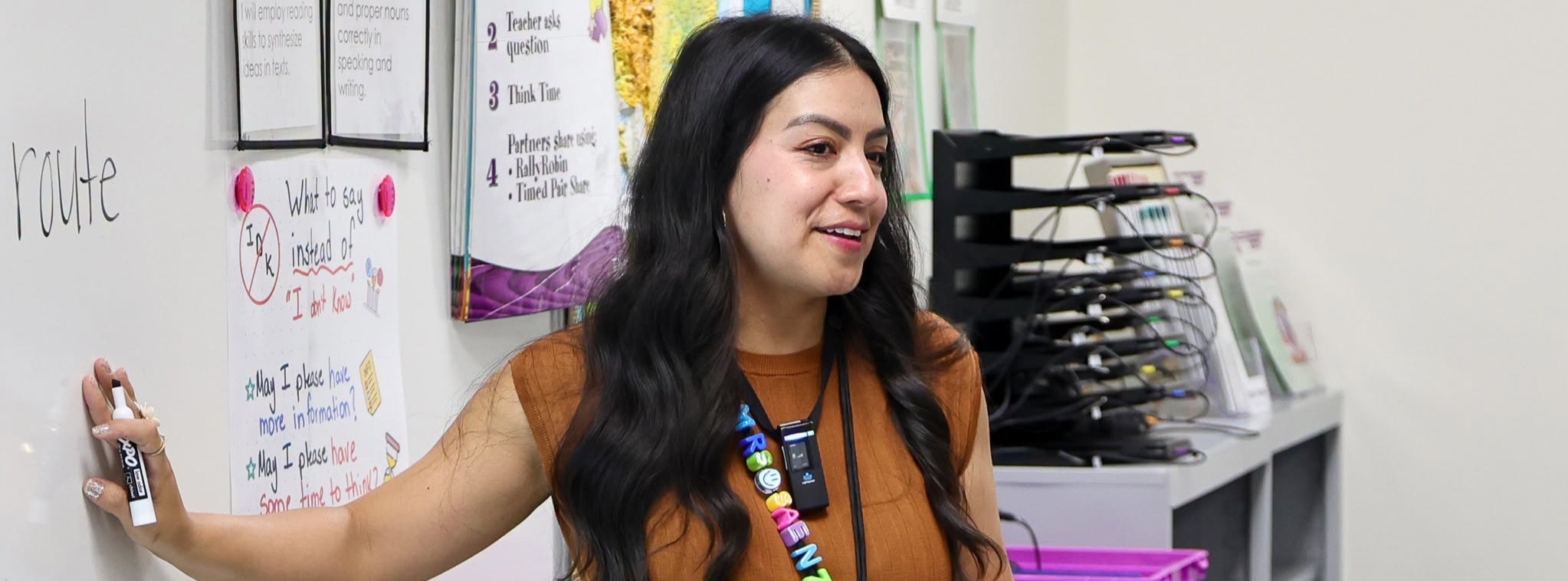 A teacher standing next to her whiteboard during a class lesson.