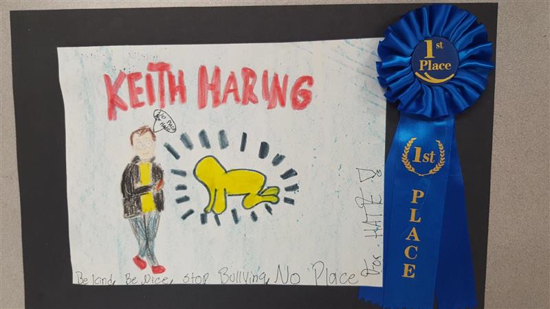 A colorful drawing featuring the name 'Keith Haring' in red letters, alongside a cartoonish figure and a yellow figure with radiating lines, all displayed on a black background with a blue ribbon labeled '1st Place.'