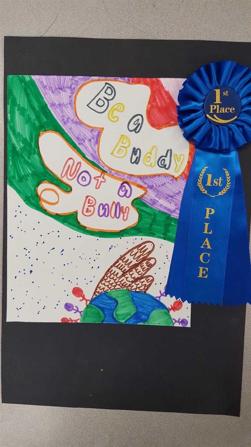 A colorful artwork featuring the phrase 'Be a Buddy, Not a Bully' surrounded by playful designs, accompanied by a blue ribbon labeled '1st Place'.