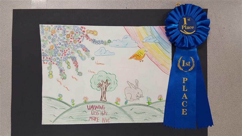 A colorful drawing featuring a tree, a rabbit, and a rainbow, accompanied by a blue ribbon labeled '1st Place'.