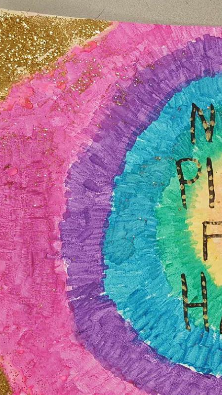 A colorful, circular artwork featuring concentric rings of pink, purple, blue, and green, with the letters 'N P I H' inscribed in the center.