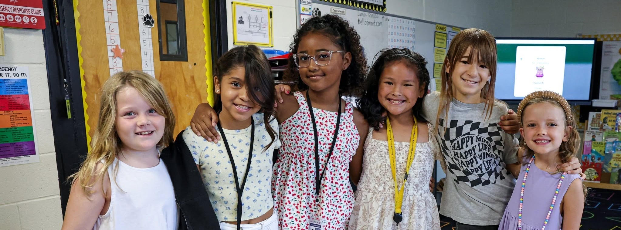 A group of young girls grouped together for a photo in the classroom.