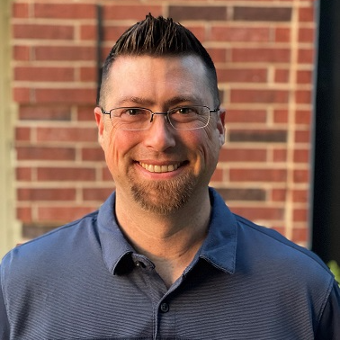A man with short hair and glasses smiling