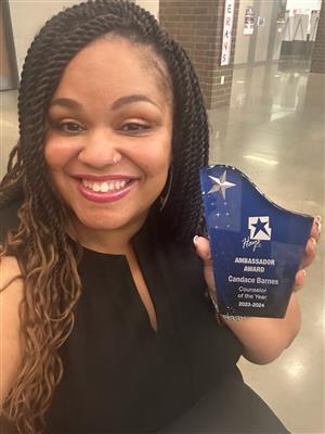 A woman smiling while carrying an award for Ambassador Awards