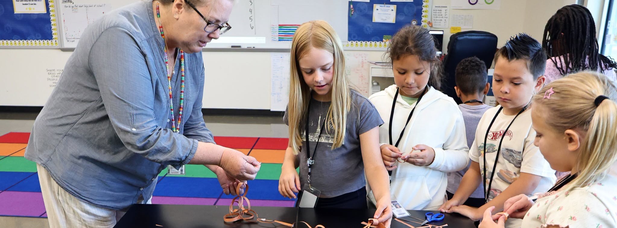 A teacher with a small group of elementary students making paper chains.