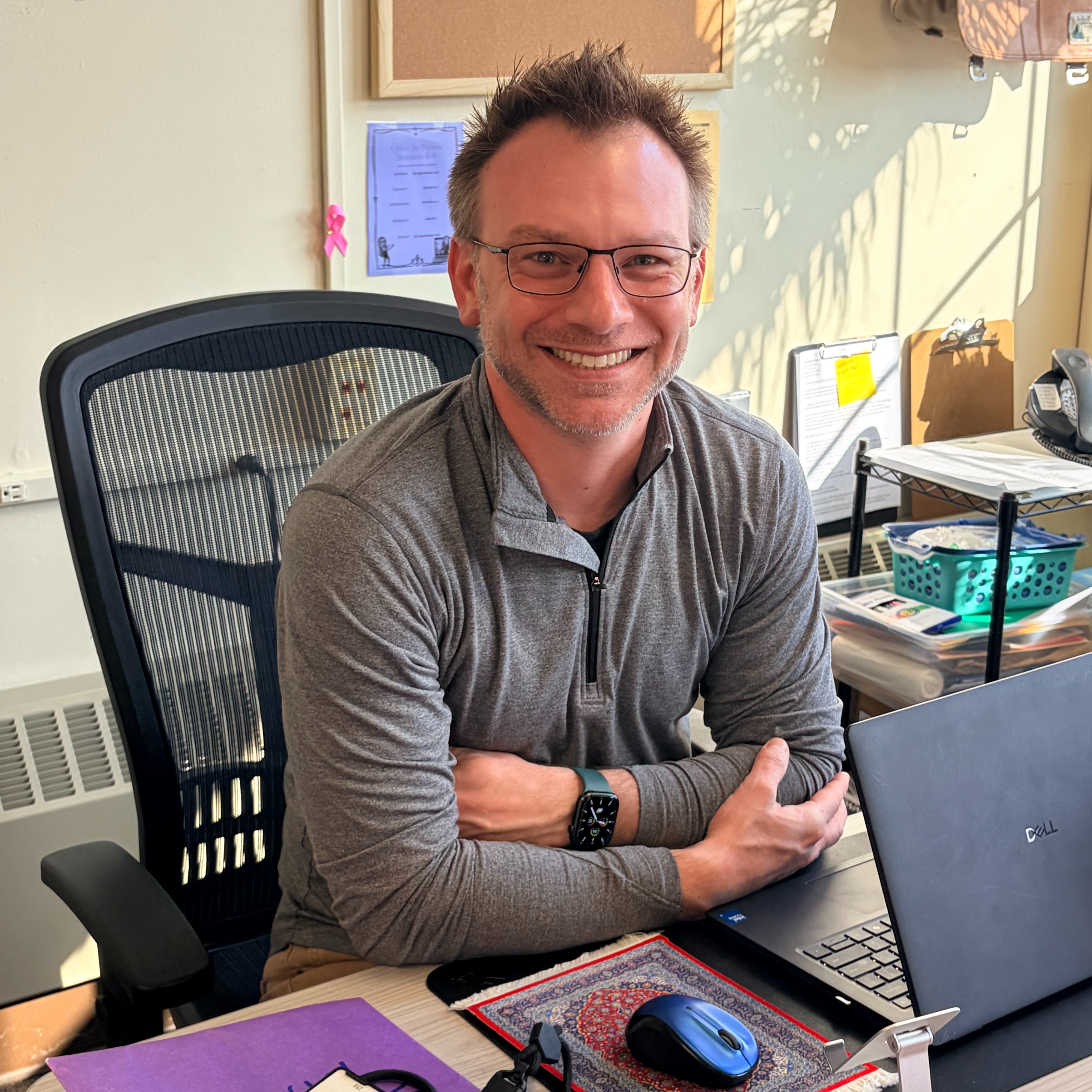 Educator smiling at his desk.