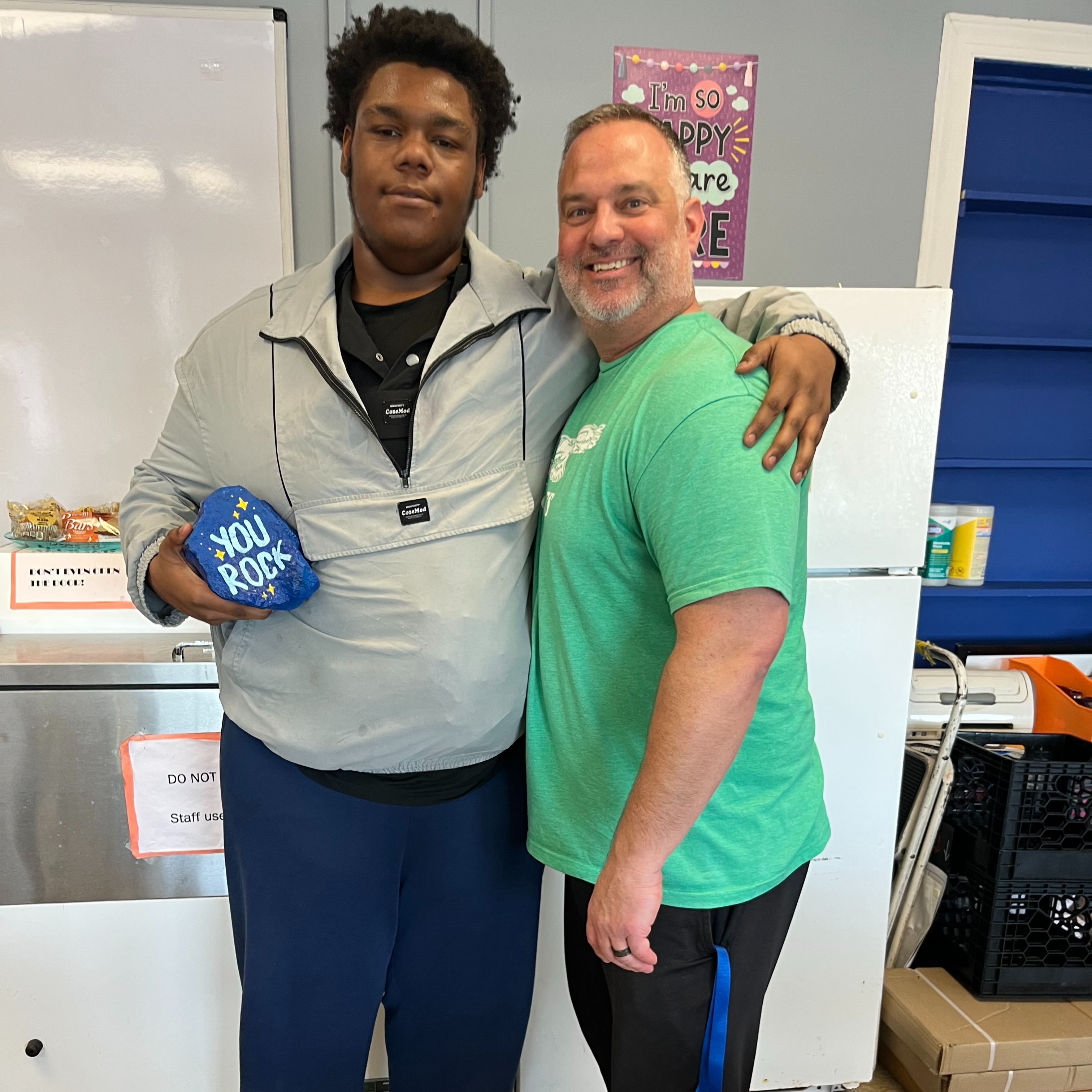 Student of the month and the school principal posing with the "You Rock" award.