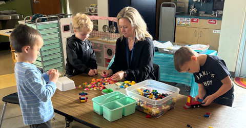 Woman playing legos with three kids